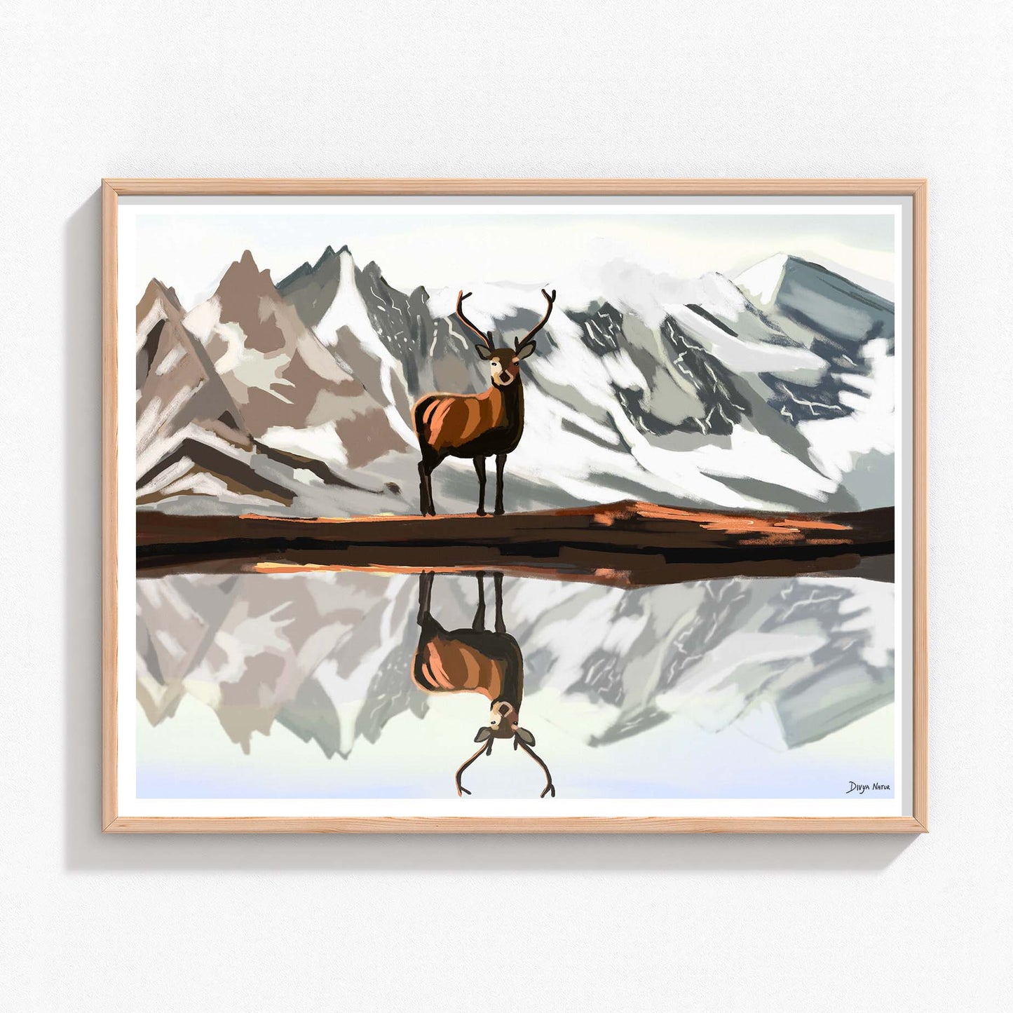 Lone elk standing before snow-capped mountains with its reflection in a lake.