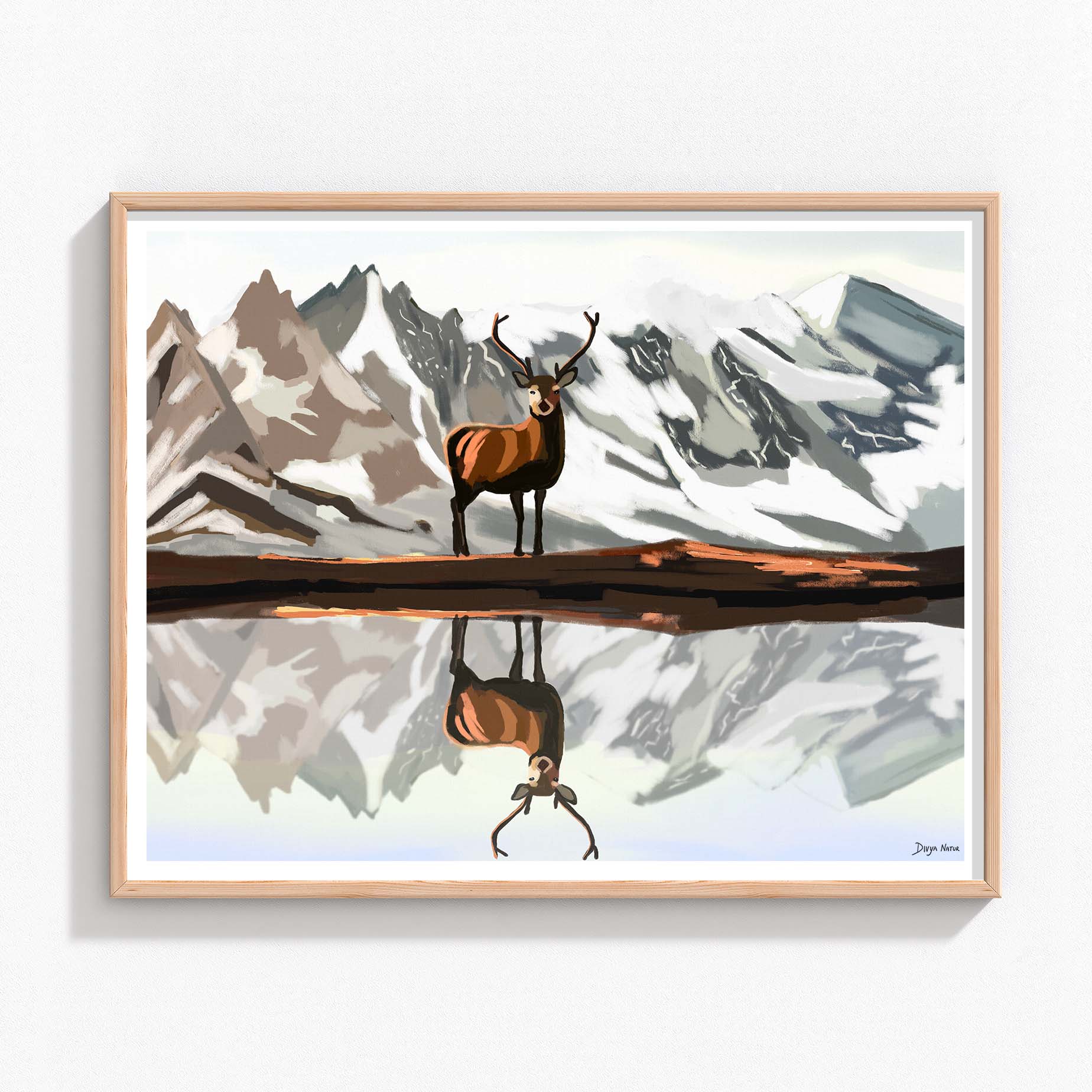 Lone elk standing before snow-capped mountains with its reflection in a lake.